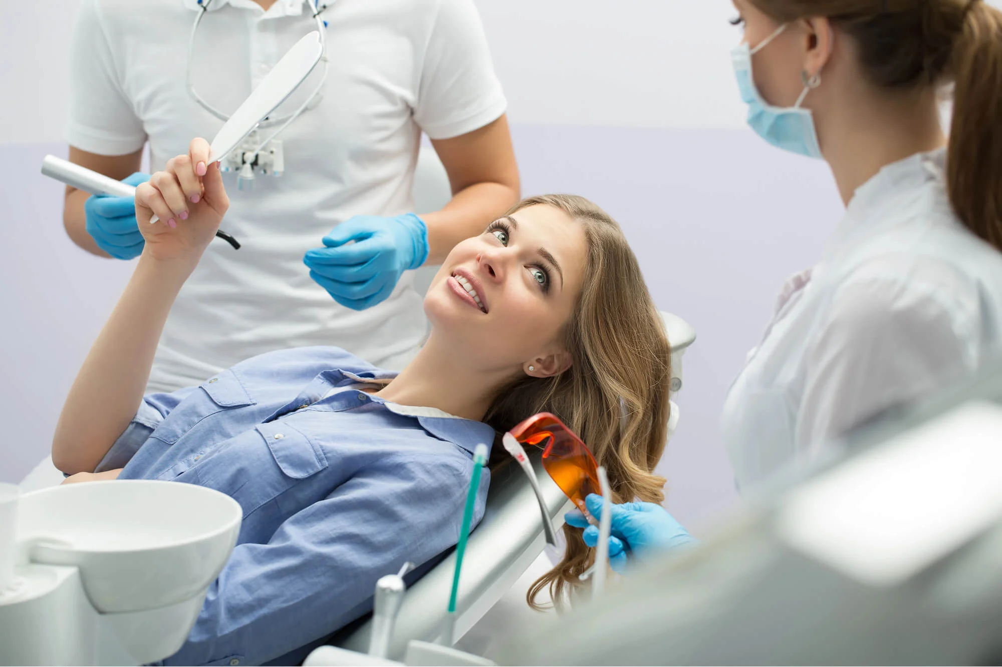 Smiling woman holding mirror at dental clinic dentist in Fort Pierce