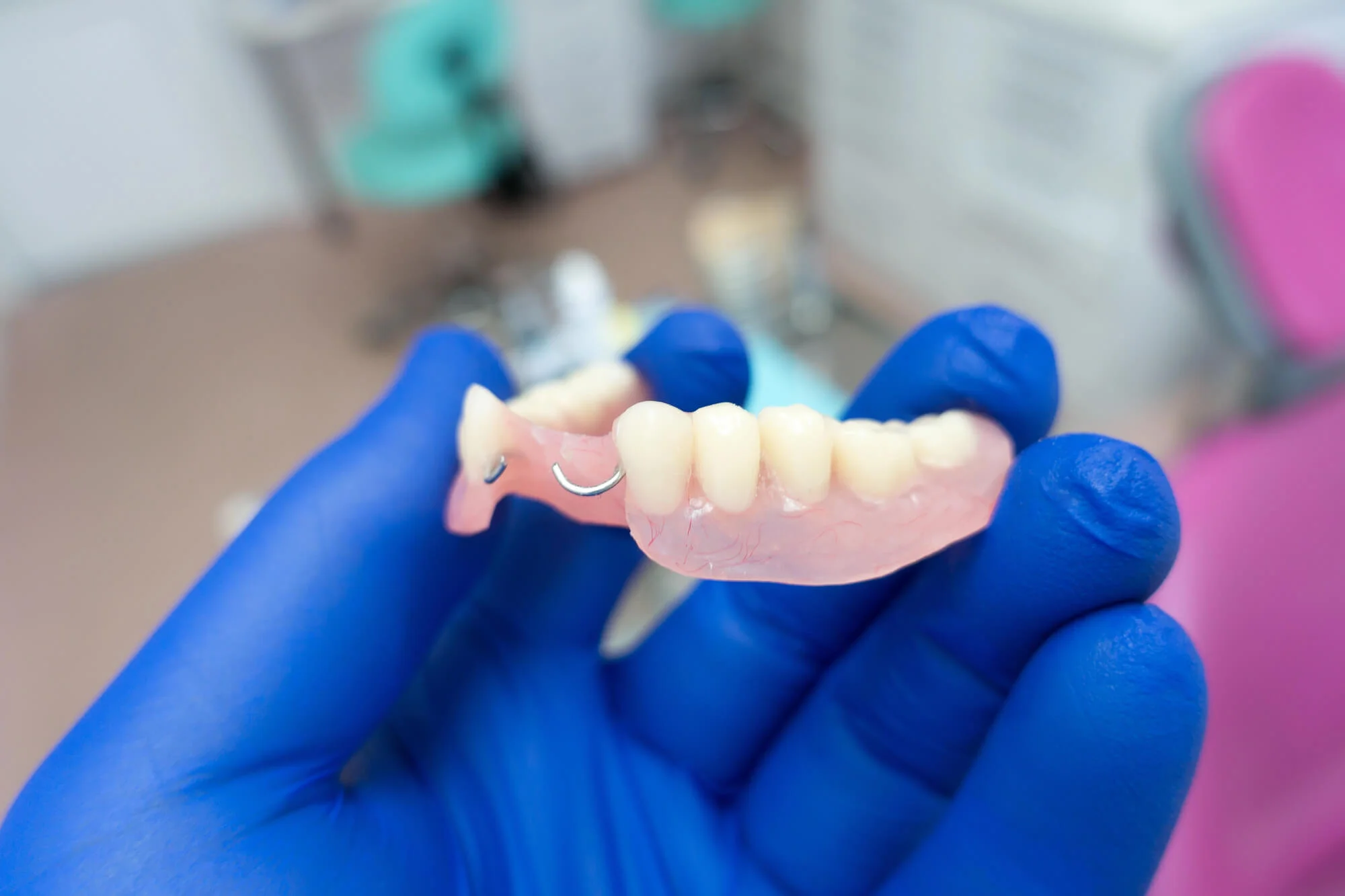 Gloved hand holding a partial denture, dentures in Fort Pierce