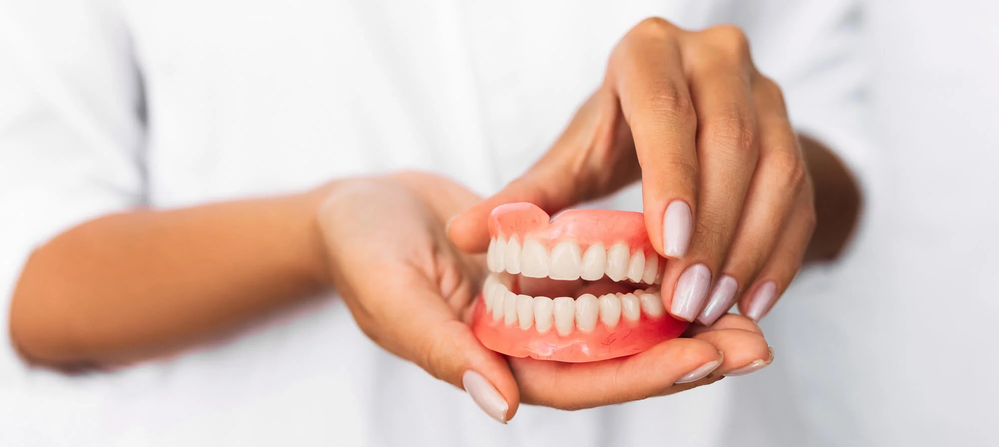 Hands holding a full denture model, dentures in Fort Pierce