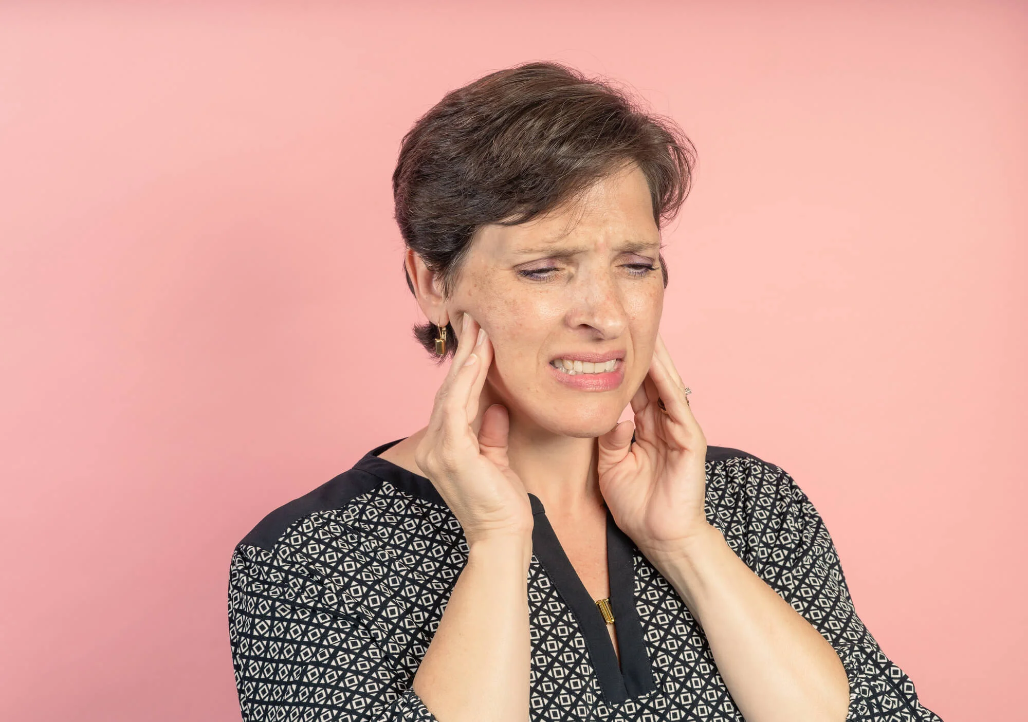 Woman with jaw pain touching cheeks emergency dentist in Fort Pierce